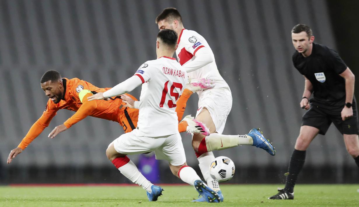 Gelandang Belanda, Georginio Wijnaldum, terjatuh saat berebut bola dengan bek Turki, Ozan kabak, pada laga kualifikasi Piala Dunia 2022 di Stadion Olimpiade Ataturk, Kamis (25/3/2021). Turki menang dengan skor 4-2. (Tolga Bozoglu/Pool Photo via AP)