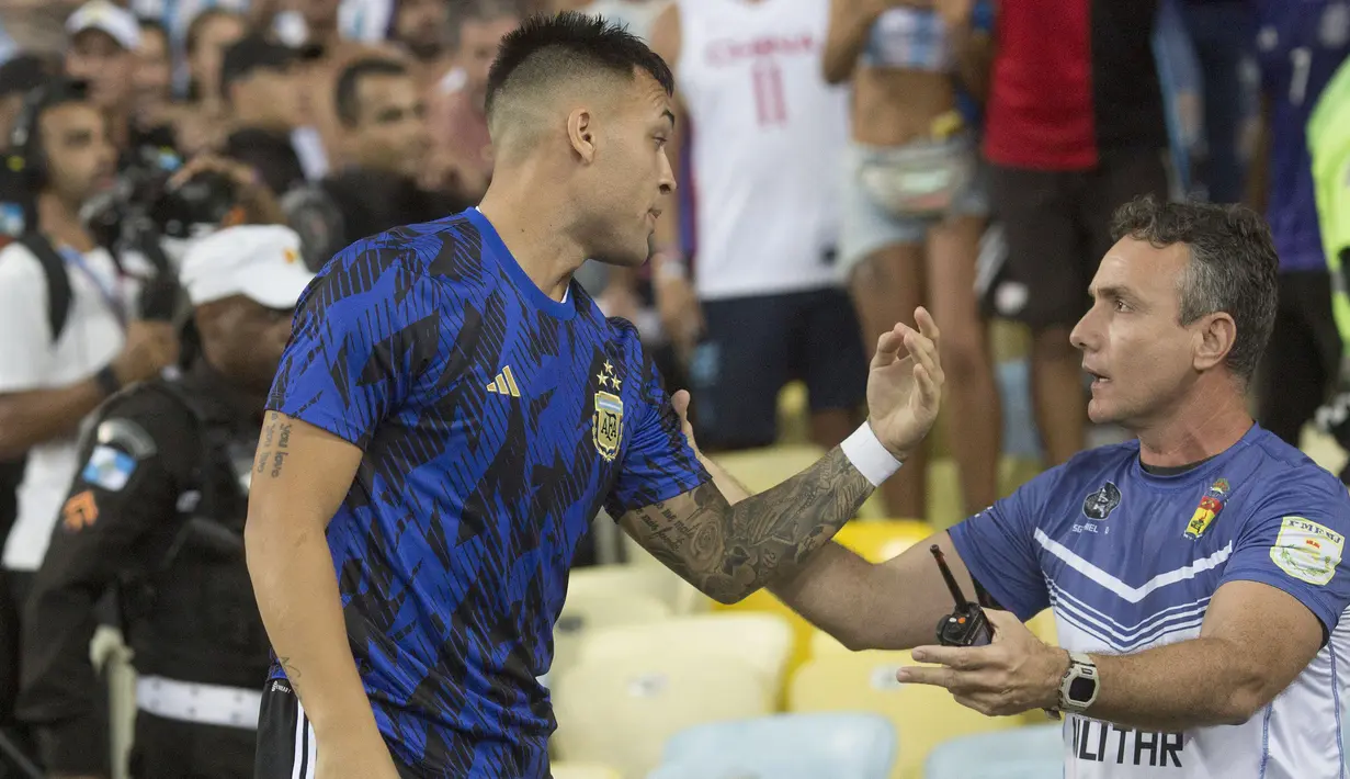 Pemain Argentina, Lisandro Martinez (kiri) berbicara dengan petugas keamanan saat kericuhan sebelum laga Kualifikasi Piala Dunia 2026 antara Brasil melawan Argentina di Stadion Maracana, Brasil, Rabu (22/11/2023) WIB. (AFP/Carl De Souza)