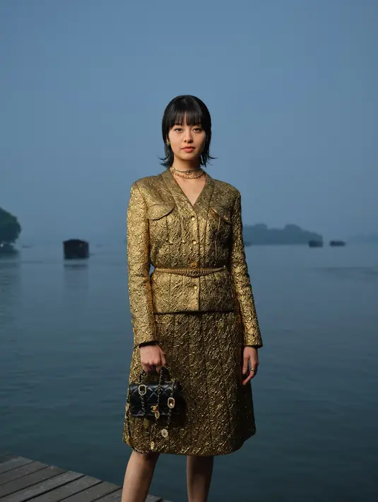 Aktris Amy Lo menutup deretan selebriti dengan penampilannya yang mewah. Ia mengenakan jacquard blazer dan midi skirt berwarna emas yang berkilau, memberikan kesan mewah dan elegan. Penampilannya menjadi sorotan utama, menambah kemewahan di acara bergengsi ini. [Dok/Chanel].