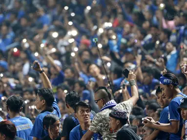 Aksi Bobotoh menyalakan lampu saat mendukung timnya melawan Persija Jakarta pada Torabika SC 2016 di Stadion Gelora Bandung Lauta Api, Bandung, Sabtu (16/7/2016). (Bola.com/Nicklas Hanoatubun)