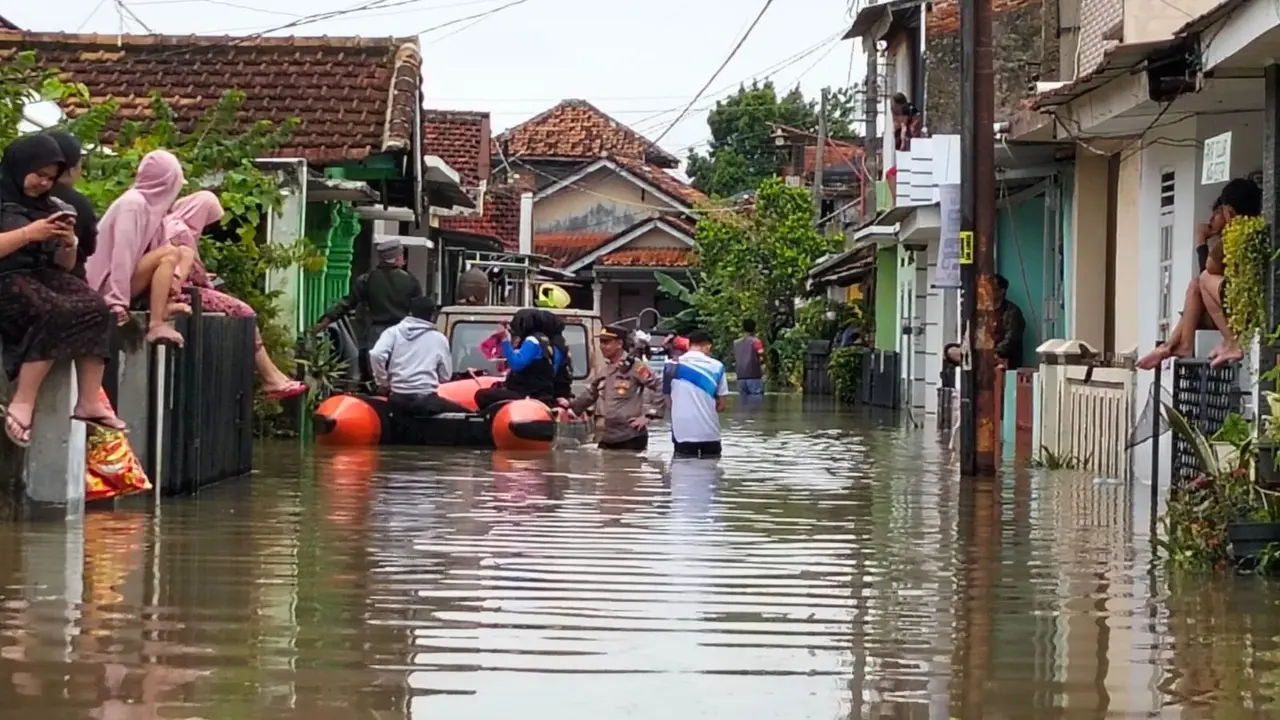 Petugas gabungan membantu mengevakuasi warga menggunakan perahu karet yang terjebak di dalam rumah di Kecamatan Tanjung Senang, Bandar Lampung. Foto : (Istimewa).