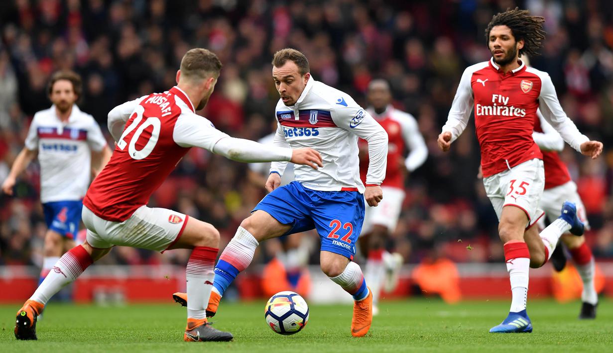 Striker Stoke, Xherdan Shaqiri, berusaha melewati bek Arsenal, Shkodran Mustafi pada laga Premier league di Stadion Emirates, London, Minggu (1/4/2018). Arsenal menang 3-0 atas Stoke. (AFP/Oliver Greenwood)