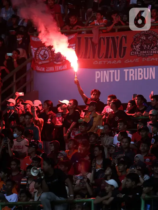 Suporter menyalakan flare saat menyaksikan laga Persija melawan Sabah FC pada laga uji coba internasional di Stadion Patriot Candrabhaga, Kota Bekasi, Minggu (5/6/2022). Pertandingan sepakbola kembali bisa disaksikan secara langsung setelah pemerintah melonggarkan aturan pemakaian masker di luar ruangan. (Liputan6.com/Helmi Fithriansyah)