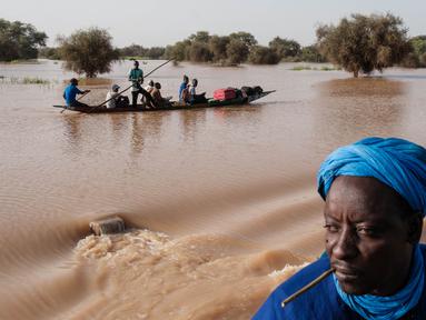 Orang-orang membawa barang-barang di atas kereta dorong di atas air banjir yang mengalir di jalan utama Odobere pada tanggal 22 Oktober 2024. (GUY PETERSON/AFP)