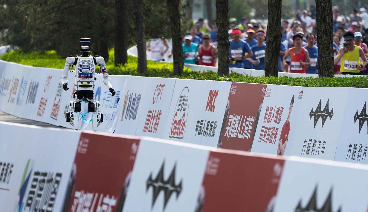 Jumlah ini meningkat signifikan dibandingkan edisi perdana tahun lalu yang hanya diikuti sekitar 20 robot. Tampak dalam foto, sebuah robot berkompetisi bersama manusia dalam ajang Beijing E-Town Half Marathon dan Humanoid Robot Half-Marathon yang diadakan di pinggiran Beijing, Minggu 19 April 2026. (AP Photo/Andy Wong)