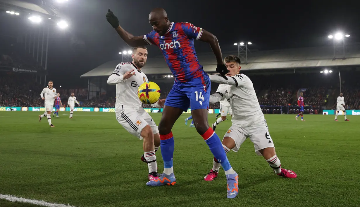 Penyerang Crystal Palace Jean-Philippe Mateta (tengah) berebut bola dengan bek Manchester United (MU) Luke Shaw (kiri) dan Lisandro Martinez pada matchday 19 Liga Inggris di Stadion Selhurst Park, London, Kamis dini hari WIB (19/1/2023). Palace akhirnya bisa menyamakan kedudukan di injury time babak kedua. (ADRIAN DENNIS / AFP)