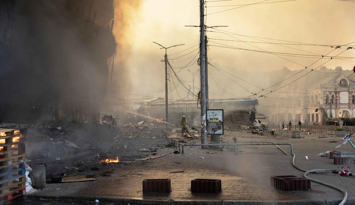 Petugas pemadam kebakaran Ukraina bekerja di lokasi di samping bangunan yang rusak parah setelah serangan Rusia di Kyiv pada Minggu 24 Mei 2026, di tengah invasi Rusia ke Ukraina. (Roman PILIPEY/AFP)