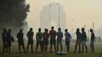 Sejumlah pria mendengarkan pelatih sebelum bermain sepak bola di tengah kondisi kabut asap tebal di New Delhi, India (30/10). Tingkat kabut melonjak selama musim dingin di Delhi, ketika kualitas udara memburuk. (AFP Photo/Prakash Singh)