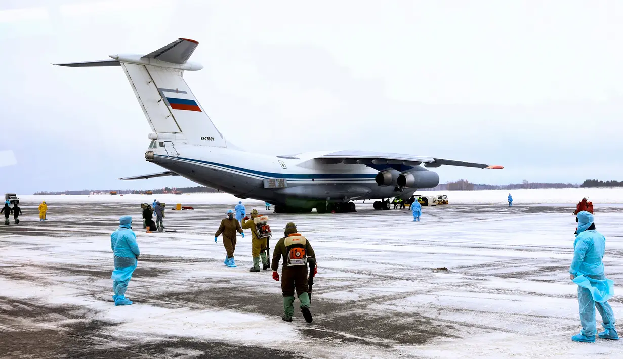 Petugas medis menyambut kedatangan warga yang turun dari pesawat militer di sebuah bandara luar Tyumen, Rusia, Rabu (5/2/2020). Seluruh warga yang dievakuasi dari Wuhan menyusul wabah virus corona tersebut akan dikarantina selama dua minggu di Siberia. (AP Photo/Maxim Slutsky)