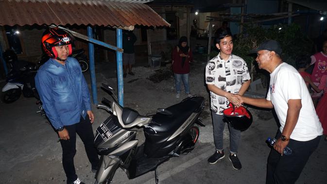 Gibran datang ke lokasi penyerahan bantuan air bersih dengan membonceng motor, Jumat (1/11).(Liputan6.com/Fajar Abrori)