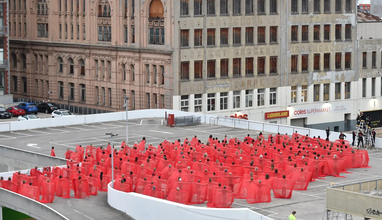 Ratusan orang berpose mengenakan kain merah transparan saat foto bugil massal dari proyek terbaru fotografer AS Spencer Tunick di tempat parkir mobil di pusat perbelanjaan di Melbourne, Australia (9/7). (AFP Photo/Paul Crock)