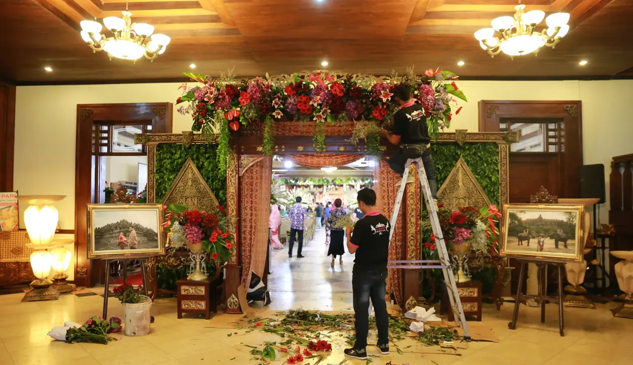 Seorang petugas sedang menyelesaikan dekorasi pintu masuk tempat berlangsungnya acara. Kembang-kembang menghias ruangan. Nuansa Jawa klasik dipilih sebagai tema dalam pernikahan Kahiyang Ayu dan Bobby Nasution. (Adrian Putra/Bintang.com)
