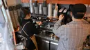 Foto yang diambil pada 26 Januari 2023 ini memperlihatkan pemilik kafe Kim Bum-soo (kanan) sedang membuat minuman kopi di kafenya di Seoul. Bahkan selama cuaca dingin di bulan Januari, toko Starbucks di Korea Selatan menjual lebih banyak es Americano -- 54 persen -- daripada yang panas. (Jung Yeon-je / AFP)