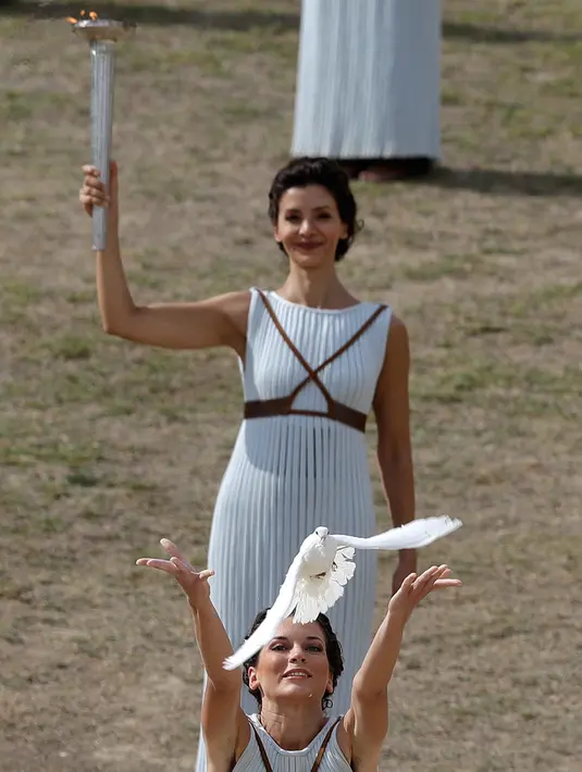 Pendeta melepaskan seekor burung merpati saat aktris Katerina Lehou yang berperan sebagai pendeta agung memegang obor selama gladi resik akhir penyalaan obor Olimpiade 2018 di Olympia Kuno, Yunani barat daya, Senin (23/10). (AP/Petros Giannakouris)