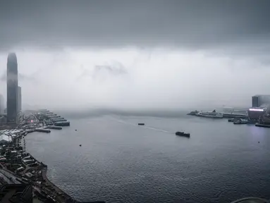 Pemandangan gedung IFC (International Finance Center) menjulang di atas dermaga Central saat badai awan terjadi sebelum hujan lebat di atas Pelabuhan Victoria Hong Kong (6/3). (AFP Photo/Anthony Wallace)