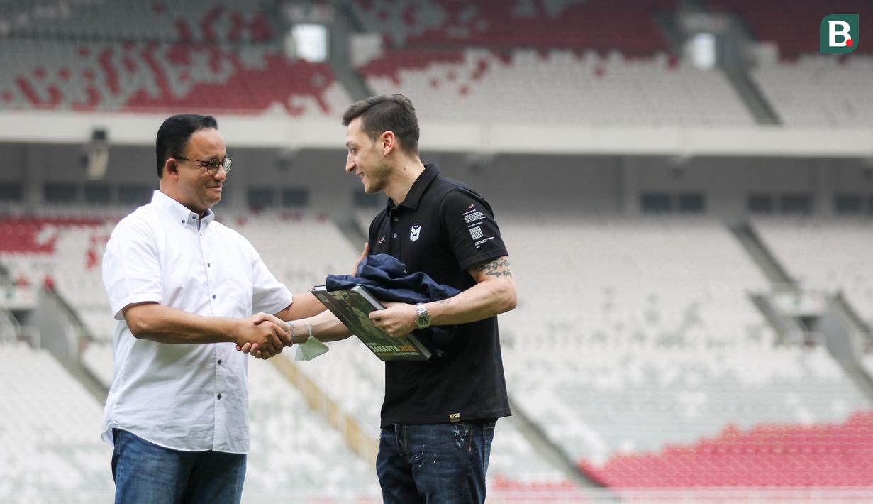 <p>Mesut Ozil (kanan) mendapat cindera mata dari Gubernur DKI Jakarta, Anies Baswedan saat menghadiri acara coaching clinic yang digelar oleh Concave Indonesia bersama 47 anak Indonesia terpilih di Stadion Utama Gelora Bung Karno (SUGBK) Senayan, Jakarta, Kamis (26/5/2022) sore WIB. (Bola.com/Bagaskara Lazuardi)</p>
