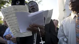 Seorang pendeta memimpin doa di luar Gereja Emanuel, Charleston, Amerika Serikat, Minggu (21/6/2015). Gereja tersebut dibuka kembali untuk ratusan jemaat yang berkabung usai penembakan yang menewaskan 9 orang. (REUTERS/Carlo Allegri) 