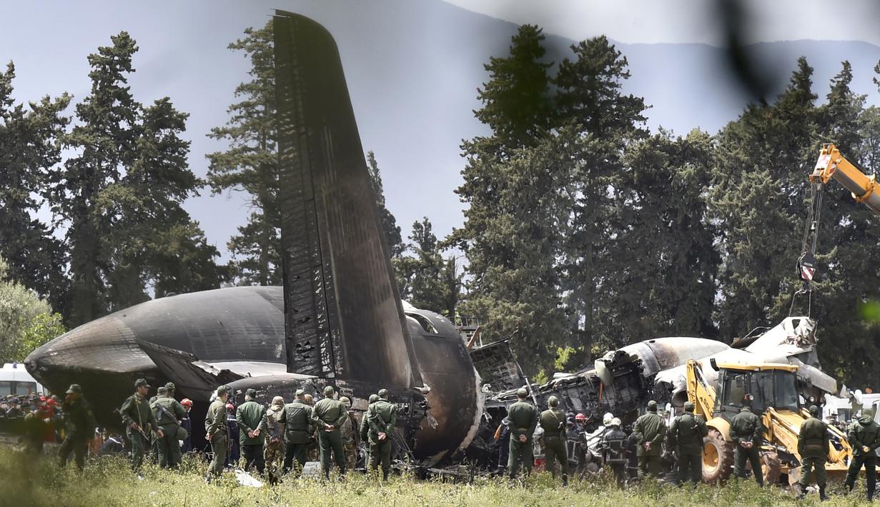 Petugas keamanan dan tim penyelamat berjaga di sekitar reruntuhan pesawat tentara Aljazair yang jatuh di dekat pangkalan udara Boufarik, Aljazair (11/4). (AFP Photo/Ryad Krmadi)