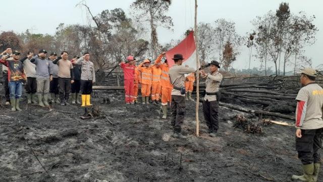 Anggota Polres Pelalawan melaksanakan upacara kemerdekaan di lokasi kebakaran lahan.