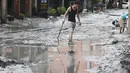 Seorang warga berjalan dengan sekop di sepanjang jalan yang tertutup lumpur di Hualien pada 24 September 2025, setelah bendungan danau jebol akibat terjangan Topan Super Ragasa. (I-Hwa Cheng/AFP)