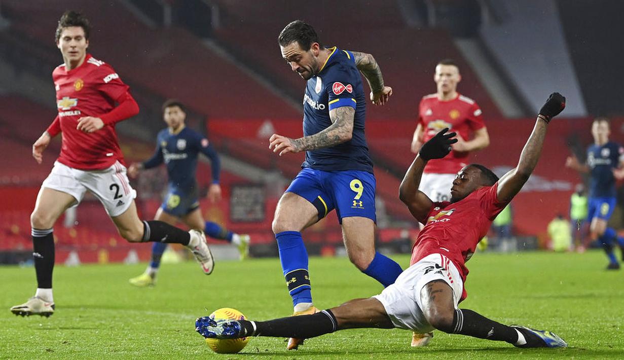 Bek Manchester United, Aaron Wan-Bissaka, berebut bola dengan pemain Southampton, Danny Ings, pada laga Liga Inggris di Stadion Old Trafford, Selasa (2/2/2021). Setan Merah menang dengan skor 9-0. (Phil Noble/Pool via AP)