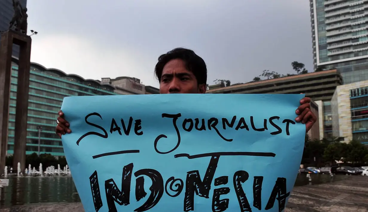 Seorang wartawan membentangkan poster saat aksi solidaritas tolak kekerasan terhadap jurnalis di Bundaran HI, Jakarta, Jumat (14/11/2014). (Liputan6.com/Johan Tallo)