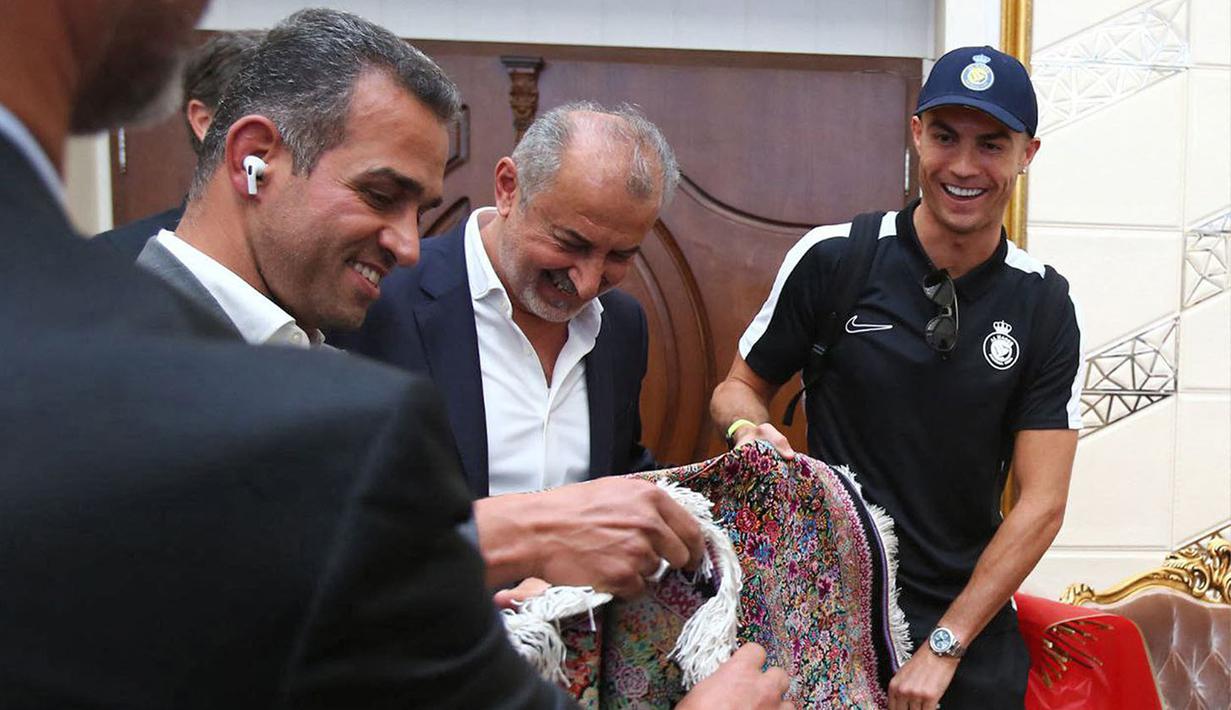 Pemain Al-Nassr, Cristiano Ronaldo menerima karpet permadani Persia saat tiba di Imam Khomeini International Airport, Tehran menjelang laga Liga Champions Asia 2023 melawan Persepolis FC, Selasa (19/09/2023). (AFP/Persepolis FC)