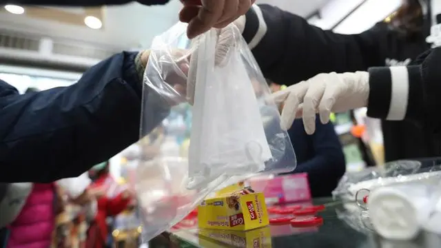 Warga menerima masker wajah gratis dalam sebuah toko di Tsuen Wan, Hong Kong, Selasa (28/1/2020).