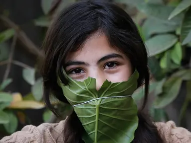 Seorang anak berpose dengan masker yang terbuat dari kubis saat dihibur oleh ibu mereka selama pandemi corona (Covid-19) di Beit Lahia di Jalur Gaza utara (16/4/2020). (AFP/Mohamed Abed)