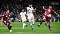 Pemain Real Madrid Karim Benzema (tengah) berebut bola dengan pemain Real Sociedad Jon Pacheco (kiri) dan Mikel Merino (kanan) pada pertandingan sepak bola Liga Spanyol di Stadion Santiago Bernabeu, Madrid, Spanyol, 5 Maret 2022. Real Madrid menang 4-1. (PIERRE-PHILIPPE MARCOU/AFP)