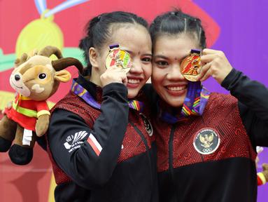 Pesilat Indonesia Riska Hermawan (kiri) dan Ririn Rinasih menunjukkan medali emas usai menjuarai nomor Seni Ganda Wanita Pencak Silat Sea Games 2021 Vietnam di Bac tu Liem Sport Center, Hanoi, Rabu (11/5/2022). (Bola.com/Ikhwan Yanuar)