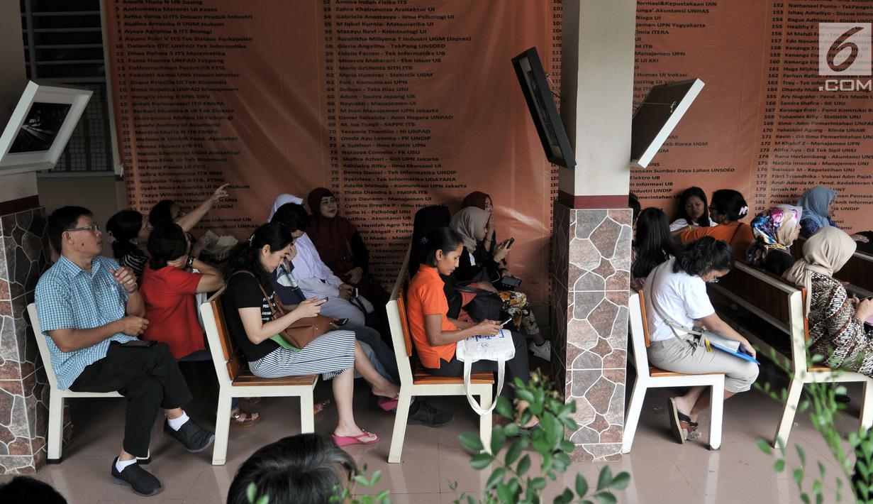 Orangtua murid menunggu antrean pengambilan nomor token PPDB DKI Jalur Zonasi di SMA Negeri 21, Jakarta, Senin (24/6/2019). Pada hari pertama, lebih dari 750 calon peserta didik baru telah mendaftar di SMA Negeri 21. (merdeka.com/Iqbal Nugroho)