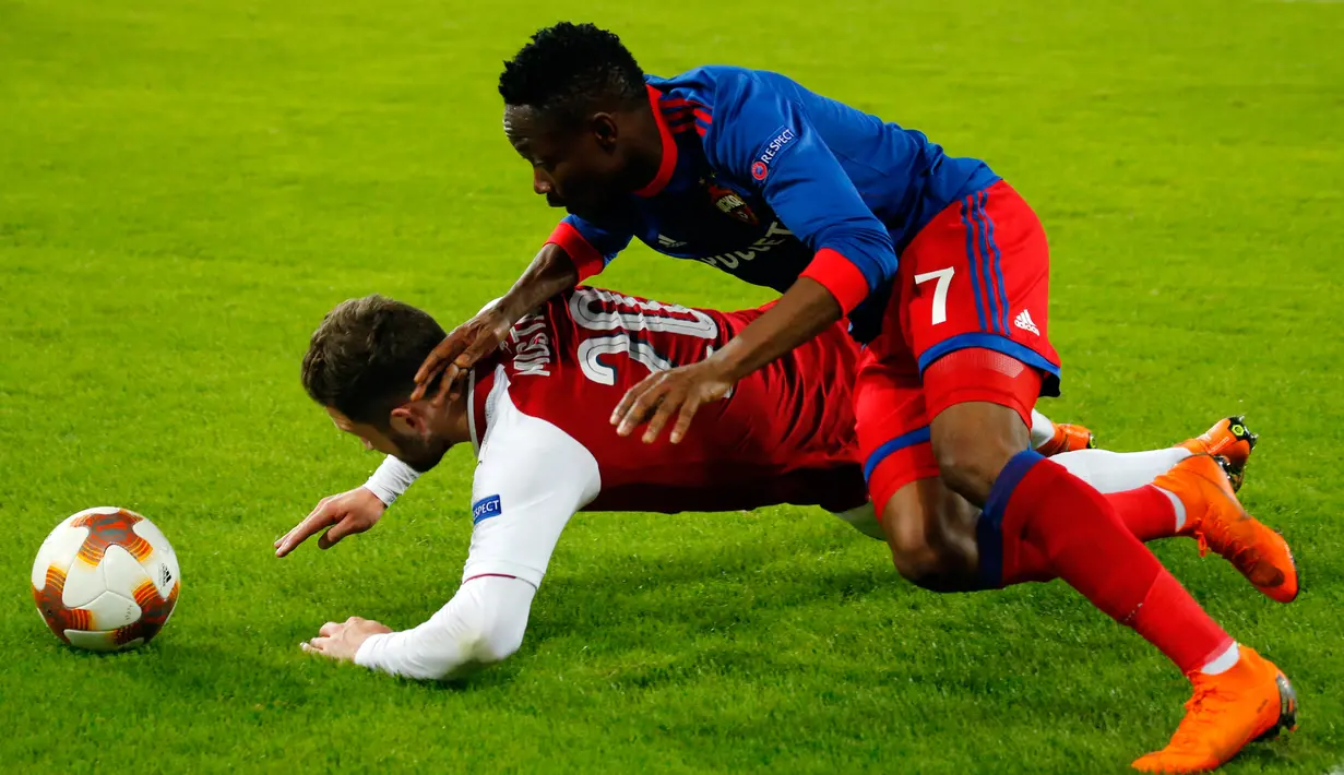 Pemain Arsenal, Shkodran Mustafi dan pemain CSKA Moscow, Ahmed Musa terjatuh saat berebut bola pada laga leg kedua perempat final Liga Europa di VEB Arena, Jumat (13/4). Berkat hasil imbang 2-2 , Arsenal unggul dengan agregat 6-3. (AP/Pavel Golovkin)