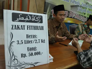 Petugas bersama seorang pria berdoa usai membayarkan zakat fitrah di Masjid Istiqlal, Jakarta, Jumat (23/6). Waktu pembayaran dibuka hingga malam takbiran dengan pembayaran zakat senilai Rp50ribu dan beras 3,5 liter. (Liputan6.com/Helmi Afandi)