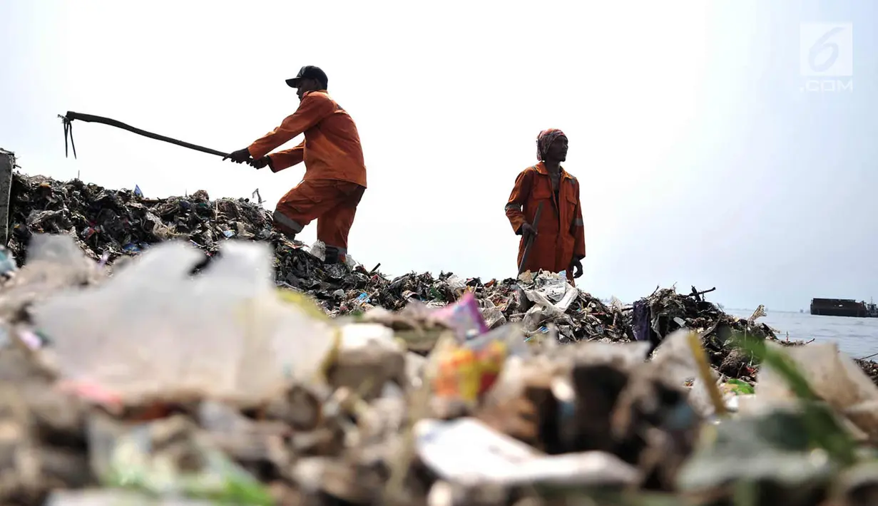 Petugas membersihkan sampah di pesisir Cilincing, Jakarta, Rabu (28/3). Tumpukan sampah tersebut memenuhi pesisir Cilincing mulai dari KBN Marunda hingga pemukiman warga yang diperkirakan mencapai ratusan ton. (Merdeka.com/Iqbal S. Nugroho)