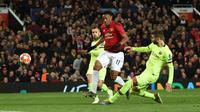 Bek Barcelona, Gerard Pique memblok tendangan bola pemain depan Manchester United, Anthony Martial pada leg pertama perempat final Liga Champions di Stadion Old Trafford, Rabu (10/4). Barcelona menang tipis 1-0 atas Manchester United. (Oli SCARFF / AFP)
