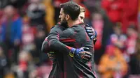 Kiper Liverpool, Alisson Becker (kanan) memeluk rekannya, Caoimhin Kelleher di sela sesi pemanasan jelang menghadapi Crystal Palace pada laga pekan ke-33 Premier League 2023/2024 di Anfield Stadium, Liverpool, Minggu (14/4/2024). (AFP/Paul Ellis)