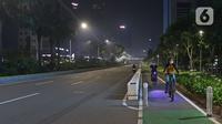 Warga bersepeda di jalan lengang kawasan Sudirman, Jakarta, Rabu (12/5/2021) malam. Polda Metro Jaya memberlakukan crowd free night untuk mencegah kerumunan takbir keliling di malam Idul Fitri 1442 yang berlaku mulai pukul 22:00 malam ini. (Liputan6.com/Herman Zakharia)