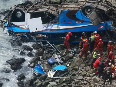 Petugas pemadam kebakaran mengevakuasi tubuh korban dari sebuah bus yang jatuh dari tebing setelah ditabrak oleh truk trailer, di Pasamayo, Peru, Selasa (3/1). Sedikitnya 35 orang tewas dalam insiden tersebut. (Vidal Tarky, Andina News Agency via AP)