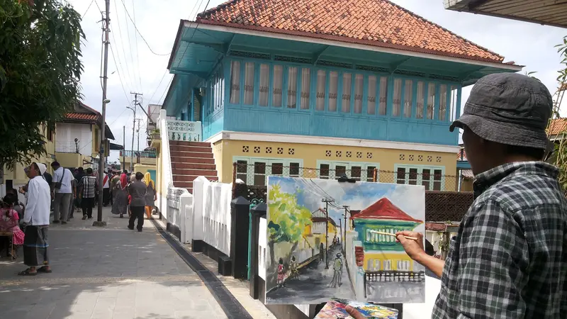 Pelukis di Palembang menggambarkan suasana Kampung Arab Al-Munawar Palembang dikertas kanvas (Liputan6.com/Nefri Inge)