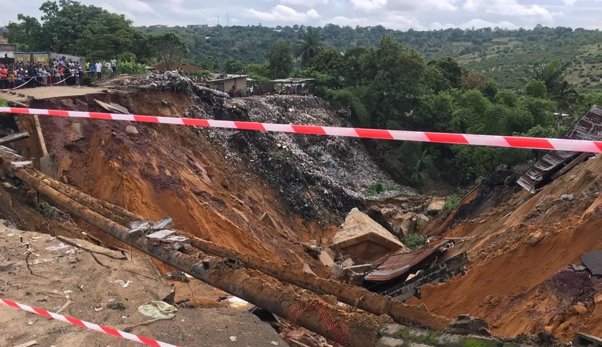 Permukaan jalan ambruk oleh tanah longsor yang disebabkan hujan lebat melanda distrik Lemba, Kinshasa di Republik Demokratik Kongo pada Selasa (26/11/2019). Menurut seorang pejabat terkemuka di Kota Kinshasa, ada tiga puluh enam orang tewas tertimbun tanah longsor. (AFP/Ange Kasongo)