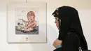 Pengunjung wanita Iran melihat kartun Presiden AS Donald J. Trump di sebuah pameran kartun Trumpisme 2017 Internasional dan kontes karikatur, di ibukota Teheran, Iran (3/7). (AFP Photo/Atta Kenare)