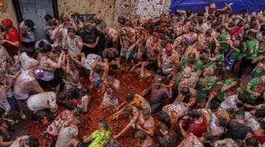 Orang-orang yang bersuka ria saling melempar tomat selama pesta pertarungan tomat tahunan "Tomatina", di desa Bunol dekat Valencia, Spanyol, Rabu (28/8/2024).  (AP Photo/Alberto Saiz)