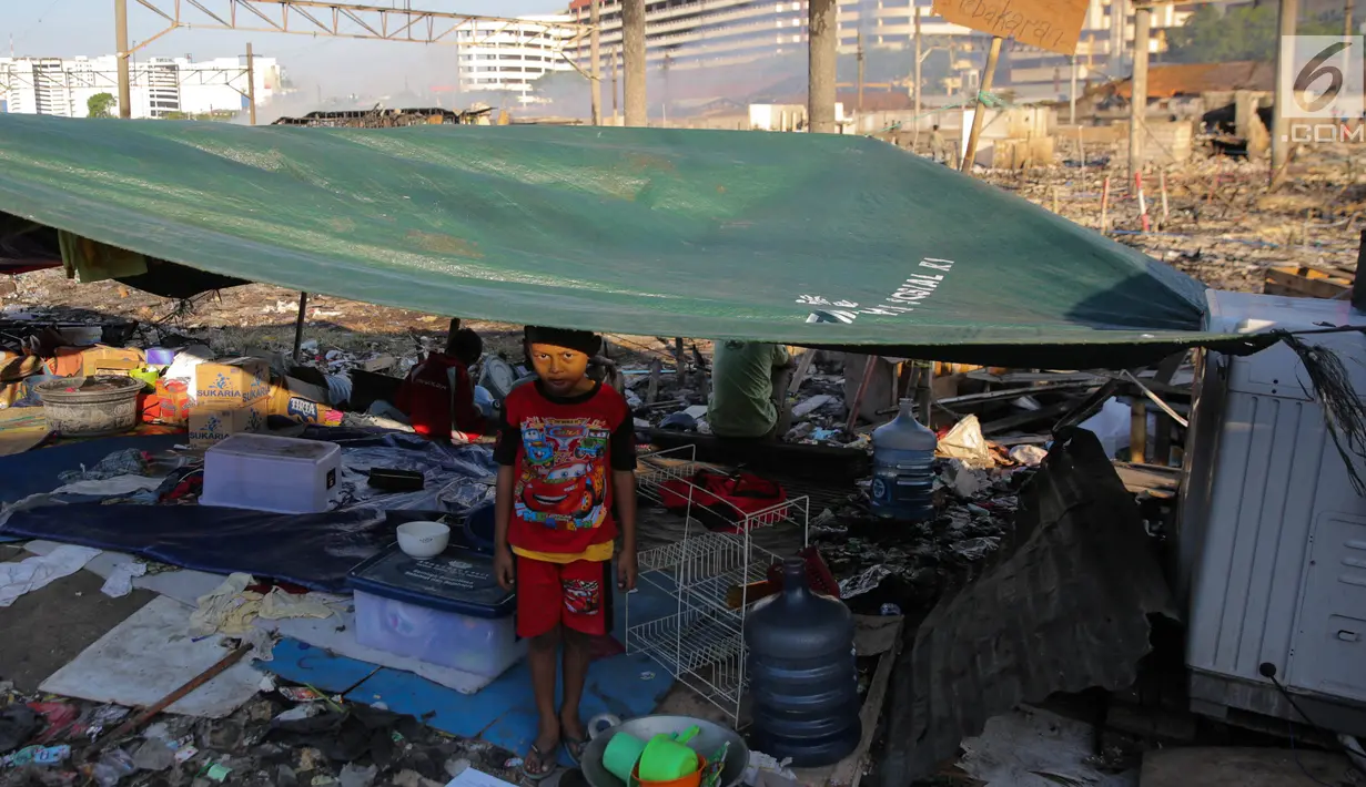 Seorang anak berdiri di tenda darurat pasca kebakaran di Kampung Bandan, Jakarta, Senin (18/9). Hari kedua pasca kebakaran warga masih bertahan di lokasi bekas kebakaran dengan membangun tenda seadanya. (Liputan6.com/Faizal Fanani)