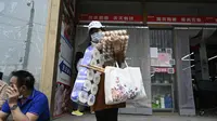 Seorang wanita meninggalkan supermarket setelah membeli makanan dan perlengkapan rumah tangga di Beijing pada 25 April 2022. Kekhawatiran penguncian Covid memicu pembelian panik dan antrean panjang untuk pengujian massal di Beijing pada 25 April ketika otoritas China bergegas untuk membasmi wabah di ibu kota. (AFP/Noel Celis)