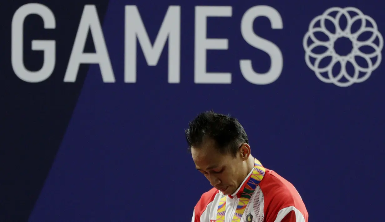 Lifter Suratman tertunduk saat naik podium usai mendapatkan medali perunggu SEA Games 2019 cabang angkat besi nomor 55 kg di Stadion Rizal Memorial, Manila, Minggu (1/12). Dirinya meraih perak dengan total angkatan 250 kg. (Bola.com/M Iqbal Ichsan)