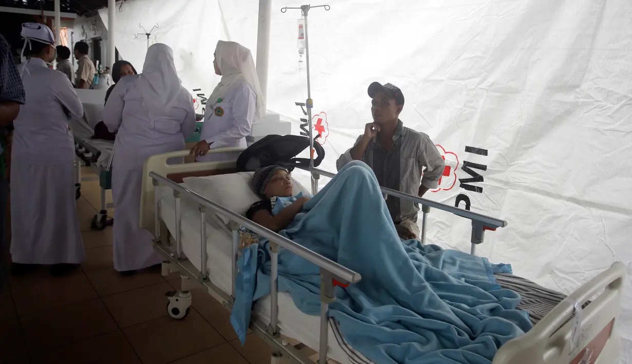 Pasien dievakuasi keluar rumah sakit di Bali menyusul gempa Lombok, Senin (6/8). Gempa 7 pada skala richter yang berpusat di Lombok, menyebabkan kerusakan bangunan di berbagai lokasi di Bali dan mengakibatkan sejumlah warga terluka. (AP/Firdia Lisnawati)