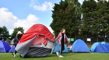 Dua wanita memindahkan tenda mereka ketika mengantre untuk membeli tiket pada hari pertama turnamen tenis Kejuaraan Wimbledon 2019 di The All England Tennis Club di Wimbledon, London barat daya (1/7/2019). Turnamen ini dimulai 1 Juli-14 Juli 2019. (AFP Photo/Ben Stansall)