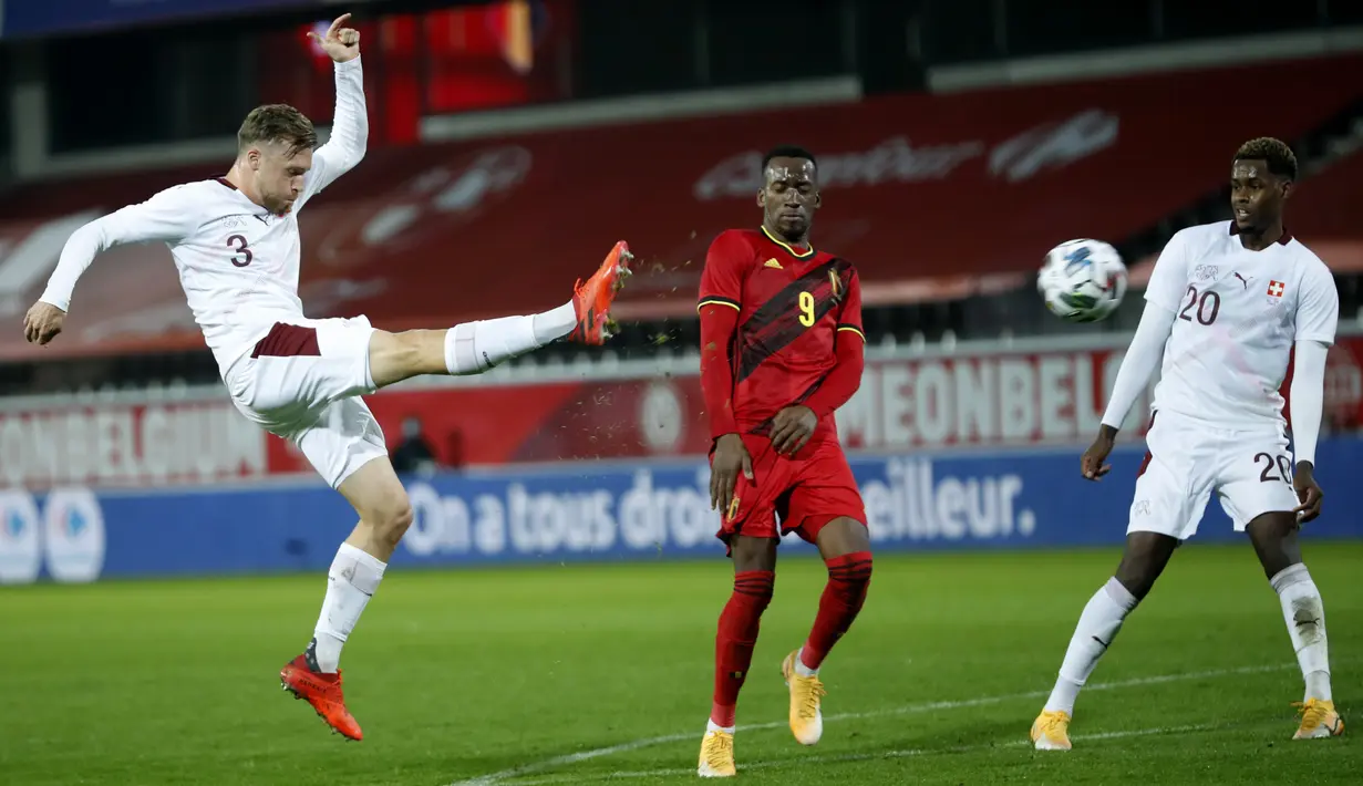Penyerang Swiss, Silvan Widmer menendang bola saat pemain Belgia Dodi Lukebakio (tengah) bertahan dalam pertandingan persahabatan di King Power Stadion At Den Dreef, Kamis (12/11/2020) dini hari WIB. Timnas Belgia Belgia mengalahkan Swiss dengan skor 2-1. (AP Photo/Francisco Seco)