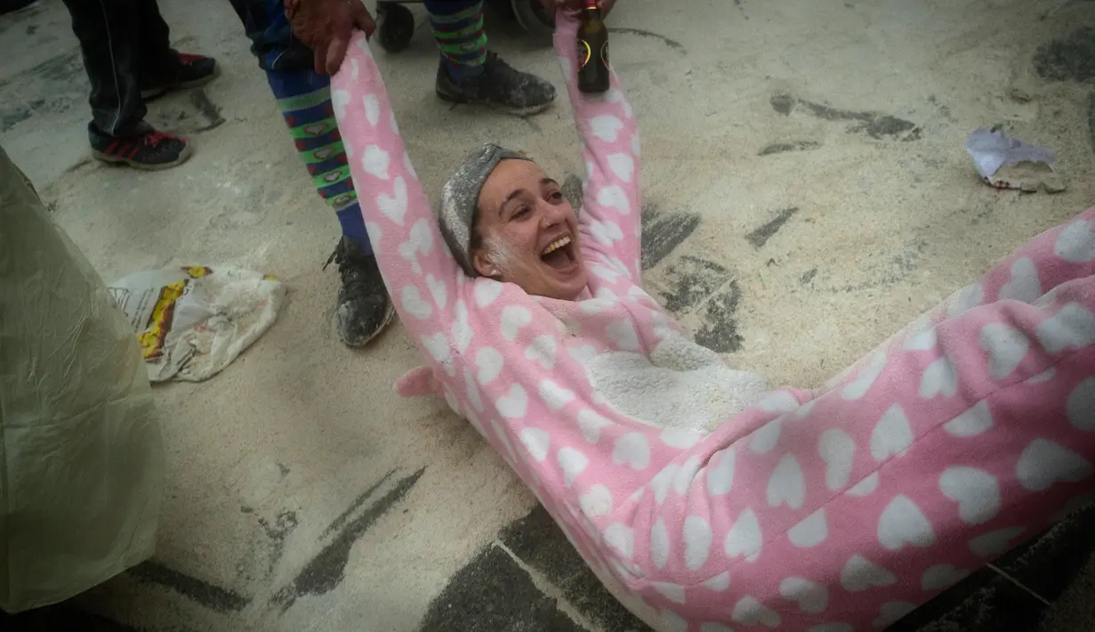 Seorang wanita diseret oleh peserta lainnya saat mengikuti festival "Domingo Fareleiro" di desa Xinzo de Limia, Spanyol (21/1). Para peserta saling melemparkan tepung dan dedak ke tetangga mereka atau wisatawan yang berkunjung. (AFP/Miguel Riopa)